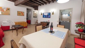 Un comedor con una mesa dispuesta para dos personas, una botella de vino y un televisor montado en la pared.