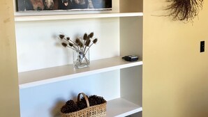A bookshelf with a framed horse painting, decorative dried plants, and books.