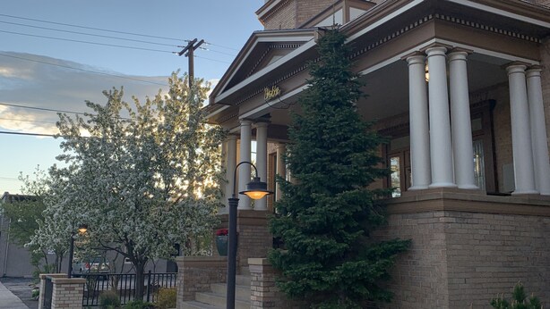 A large, multi-story building with a prominent corner turret, large columns, and a traditional architectural style.