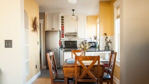 A spacious kitchen with white cabinets, a wooden dining table, and a chandelier.