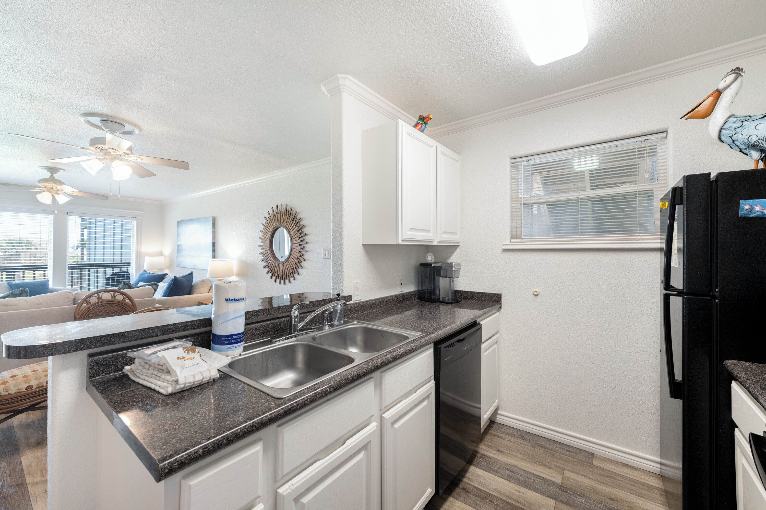 A kitchen with white cabinets, a black refrigerator, a built-in dishwasher, and a granite countertop.