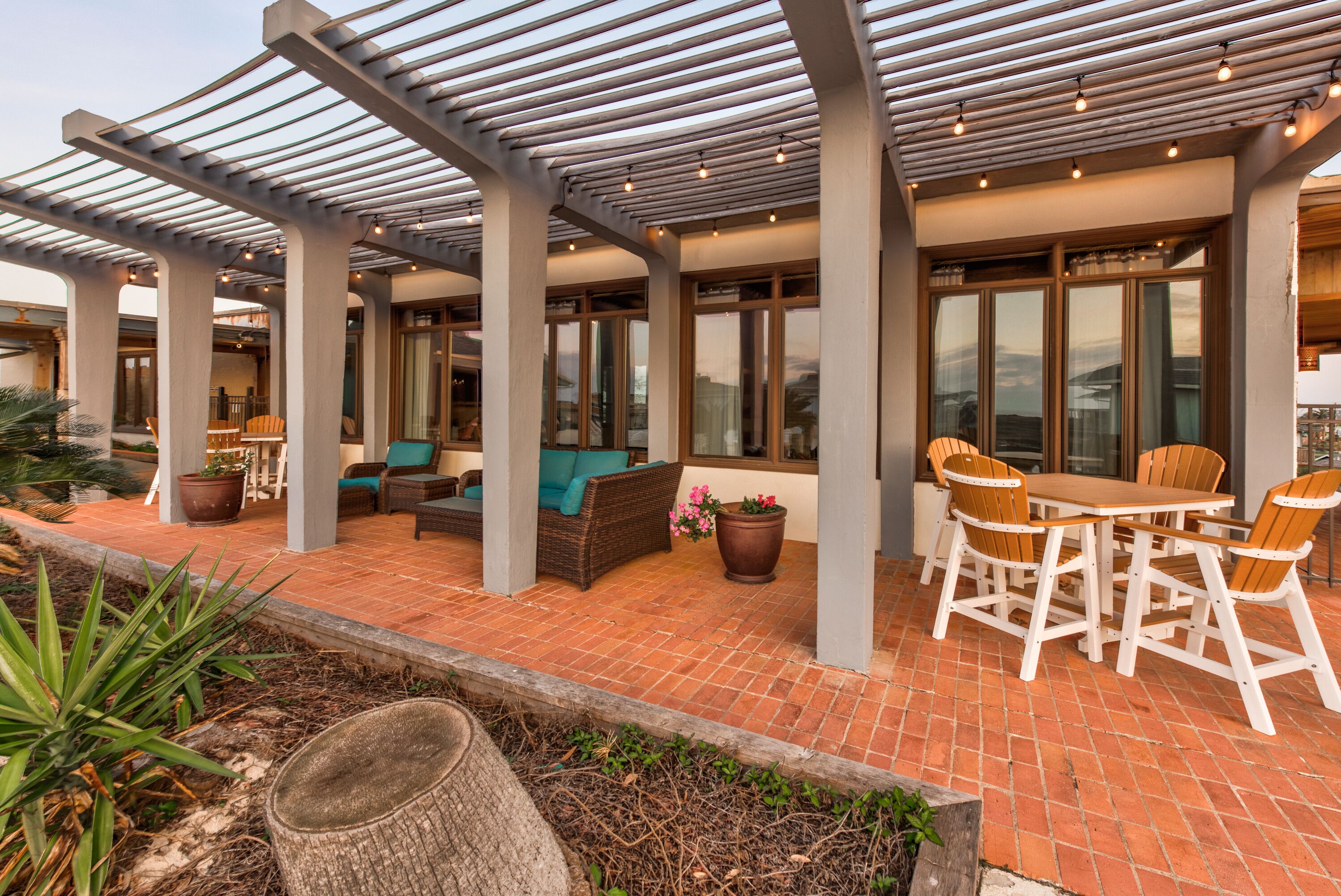 An outdoor patio area with a pergola, seating, and a dining table.