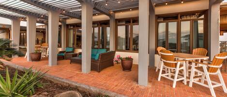An outdoor patio area with a pergola, seating, and a dining table.