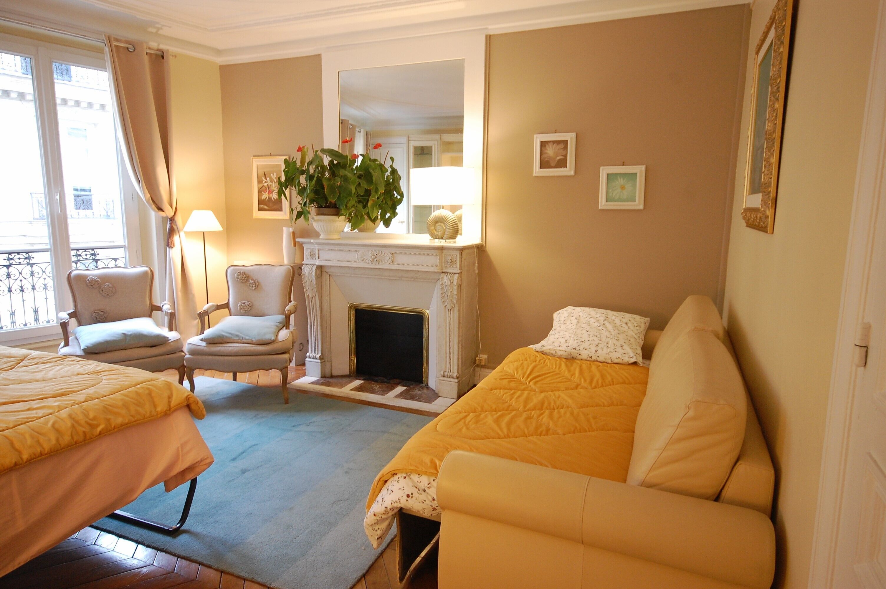 A hotel room with a bed, a sofa, a fireplace, and a balcony.