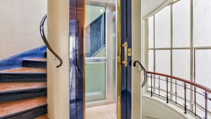 A staircase with a dark blue door, a handrail, and a view of a room with a window. - Ideal for family, friends, 2 bedrooms, 2 BR, 2 WC, 5 mn walk from Champs-Elysées (Paris)