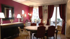 A dining area with a round table, red chairs, a mirror, and a view of the outside. - Ideal for family, friends, 2 bedrooms, 2 BR, 2 WC, 5 mn walk from Champs-Elysées (Paris)