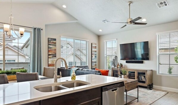A modern kitchen with a central island, built-in dishwasher, and a ceiling fan.