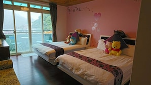 A hotel room with two beds, a balcony with a view, and decorative teddy bears.