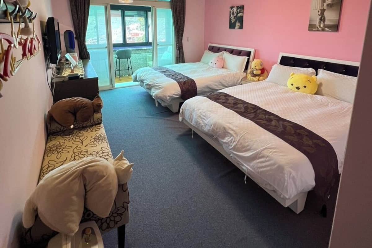 A hotel room with two beds, a desk with a computer, a chair, and a window with curtains.