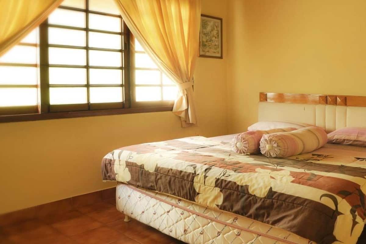A bedroom with a bed, a window with curtains, and a wall-mounted picture.
