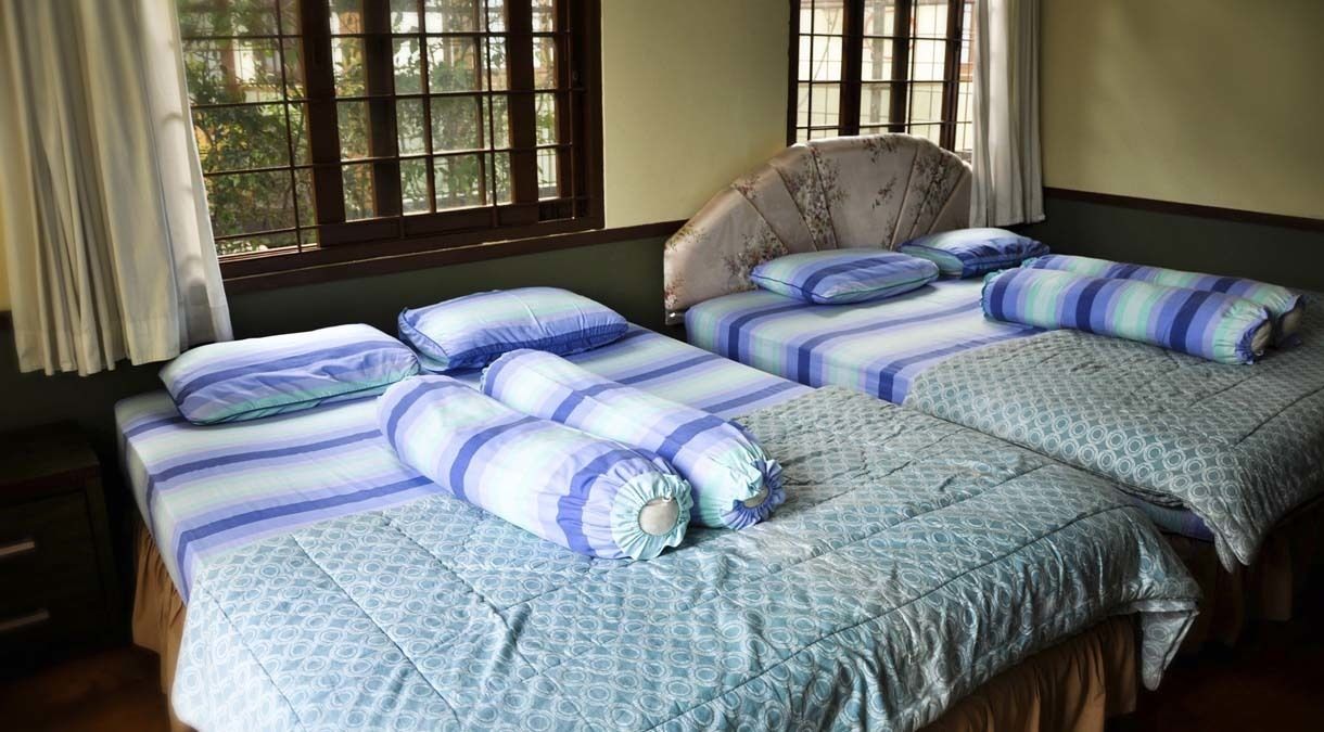 A room with two beds, each with blue and white striped bedding and matching pillows.