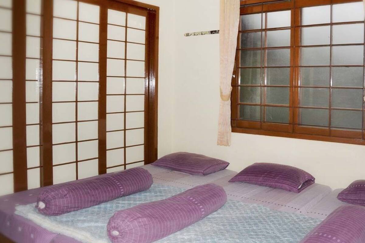A room with a bed, a window with a curtain, and a sliding door.