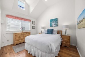 A bedroom with a large bed, wooden dresser, bedside tables, and a window with blinds. - Capitola Sea Spray by the Beach (Capitola)