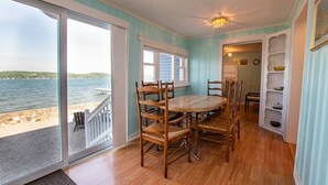 A dining area with a table and chairs, a view of the sea, and a wooden floor. - Deep Run Fun - Luxury Lake Life (Canandaigua)