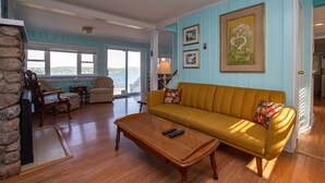 A living room with a yellow sofa, a wooden coffee table, and a stone wall. - Deep Run Fun - Luxury Lake Life (Canandaigua)