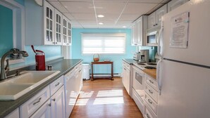 A kitchen with white cabinets, a sink, a stove, and a refrigerator. - Deep Run Fun - Luxury Lake Life (Canandaigua)