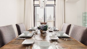 Comedor con una mesa de madera dispuesta para cuatro personas, rodeado de sillas tapizadas en gris.