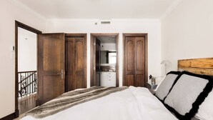 Un dormitorio con una cama grande, un armario de madera y una pequeña kitchenette al fondo.