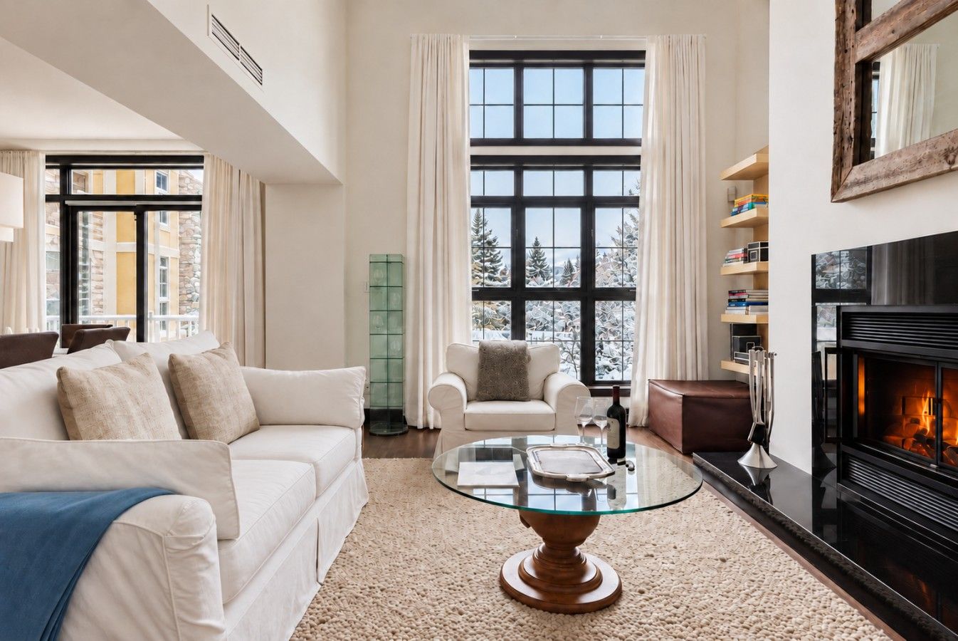 A modern living room with a fireplace, a glass coffee table, and a sofa.