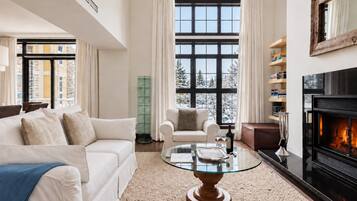 A modern living room with a fireplace, a glass coffee table, and a sofa.