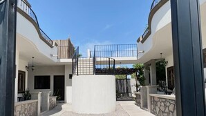 A courtyard with a central circular structure, surrounded by two-story buildings with balconies and stone walls. - Loreto80- NEW Studio Cactus, in downtown by beach (Loreto)