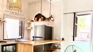 A compact kitchen with a wooden countertop, a built-in oven, and a refrigerator. There are two bar stools and a hanging light fixture above the counter. - Loreto80- NEW Studio Cactus, in downtown by beach (Loreto)