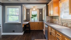A kitchen with wooden cabinets, a central island, and a window with blinds.