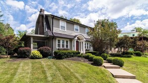 A two-story house with a front porch, a chimney, and a well-maintained lawn.
