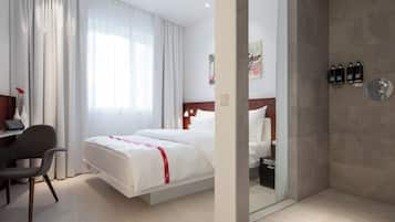 Habitación de hotel con cama, escritorio, silla y zona de ducha.
