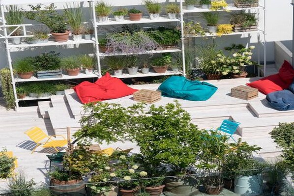 A rooftop garden with potted plants, seating areas, and a water feature. - Ruby Marie Hotel Vienna by IHG (Vienna)
