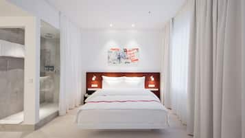 Habitación de hotel moderna con una cama grande, cabina de ducha de vidrio y vistas a la ciudad.