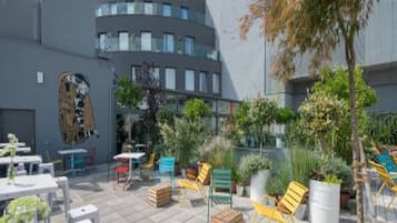 An outdoor patio area with tables and chairs, surrounded by buildings.