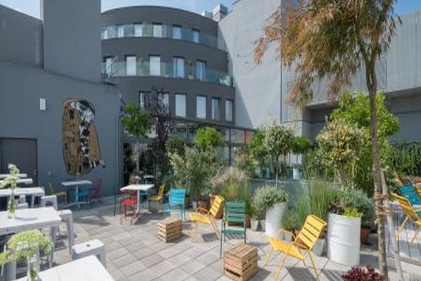 An outdoor patio area with tables and chairs, surrounded by buildings.