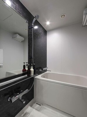 Une salle de bain moderne avec une grande baignoire, un meuble-lavabo en marbre noir et un miroir.