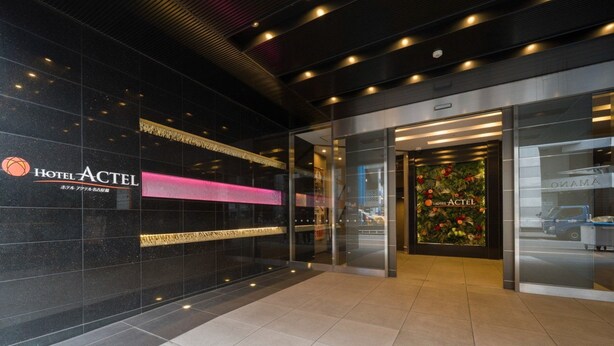 Ein Hotel mit modernem Design, das ein auffälliges Logo und eine Glastür mit einer floralen Dekoration zeigt.