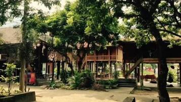 A courtyard with a wooden structure, surrounded by trees and plants.