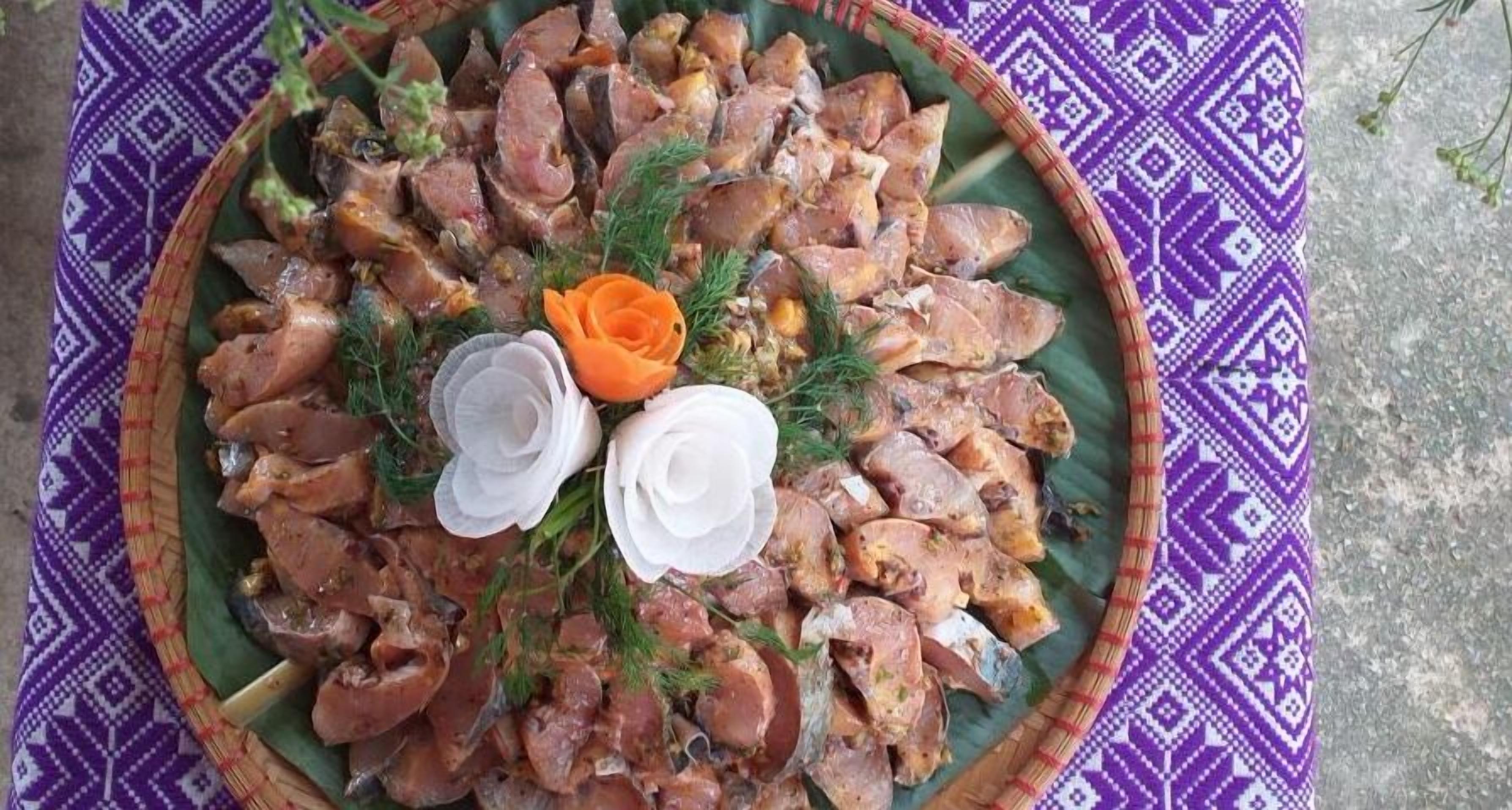A platter of cooked meat garnished with flowers and herbs.