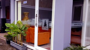 A hotel entrance with a reception desk, a large vase, and orange furniture. - Metro Malioboro Living (Yogyakarta)