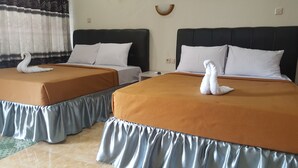 Two double beds with matching headboards and footboards, each with a swan-shaped towel on the bed. - Metro Malioboro Living (Yogyakarta)