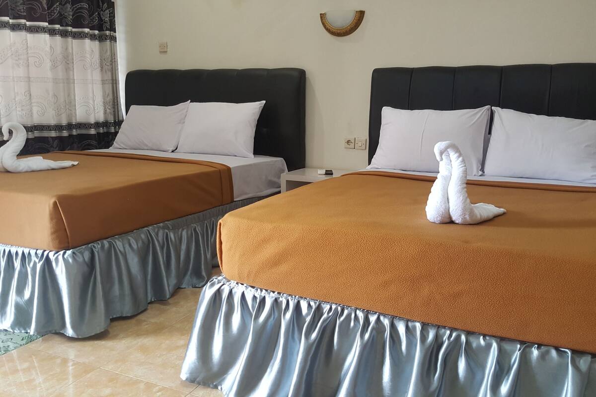 Two double beds with matching headboards and footboards, each with a swan-shaped towel on the bed.