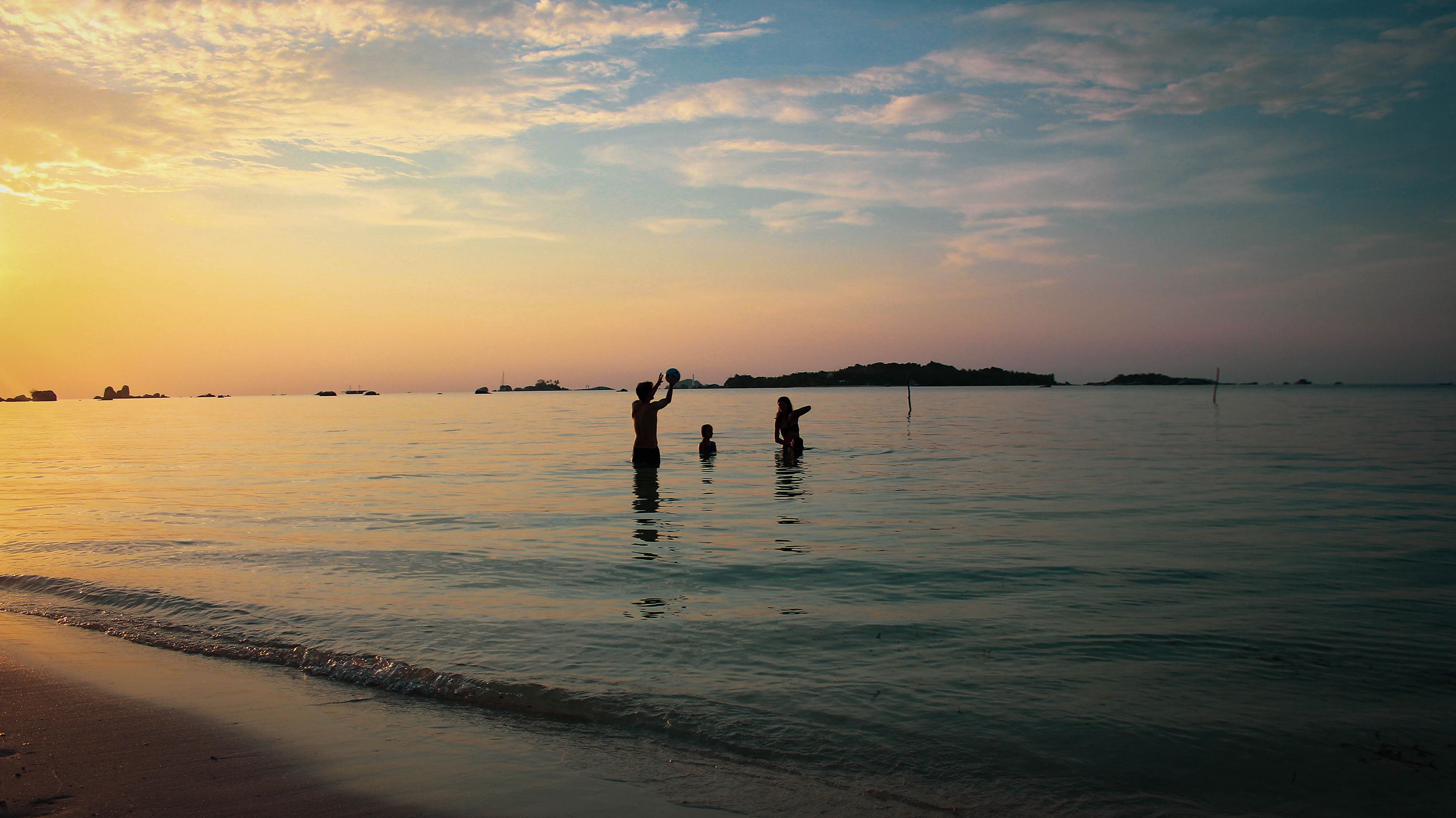 A beach scene with calm water and a sunset.