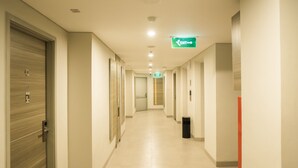 A hotel corridor with doors on both sides, a trash bin, and an exit sign. - Amaris Hotel Fachrudin – Tanah Abang (Jakarta)