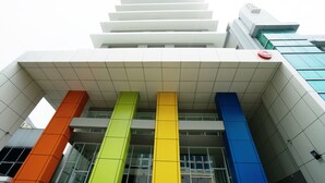 A modern building with a white facade, a red circular logo, and colorful vertical elements. - Amaris Hotel Fachrudin – Tanah Abang (Jakarta)