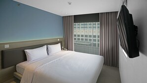 A hotel room with a large bed, a flat-screen TV mounted on the wall, and a window with curtains. - Amaris Hotel Fachrudin – Tanah Abang (Jakarta)
