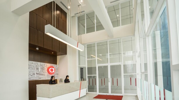 A modern reception area with a reception desk, a large glass door entrance, and a high ceiling with exposed beams. - Amaris Hotel Fachrudin – Tanah Abang (Jakarta)