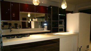 A modern kitchen with dark wood cabinets, a white countertop, and a built-in stove. - Villa Pantai Lovina (Kubutambahan)
