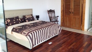 A bedroom with a bed, a chair, and a wooden door. - Villa Pantai Lovina (Kubutambahan)