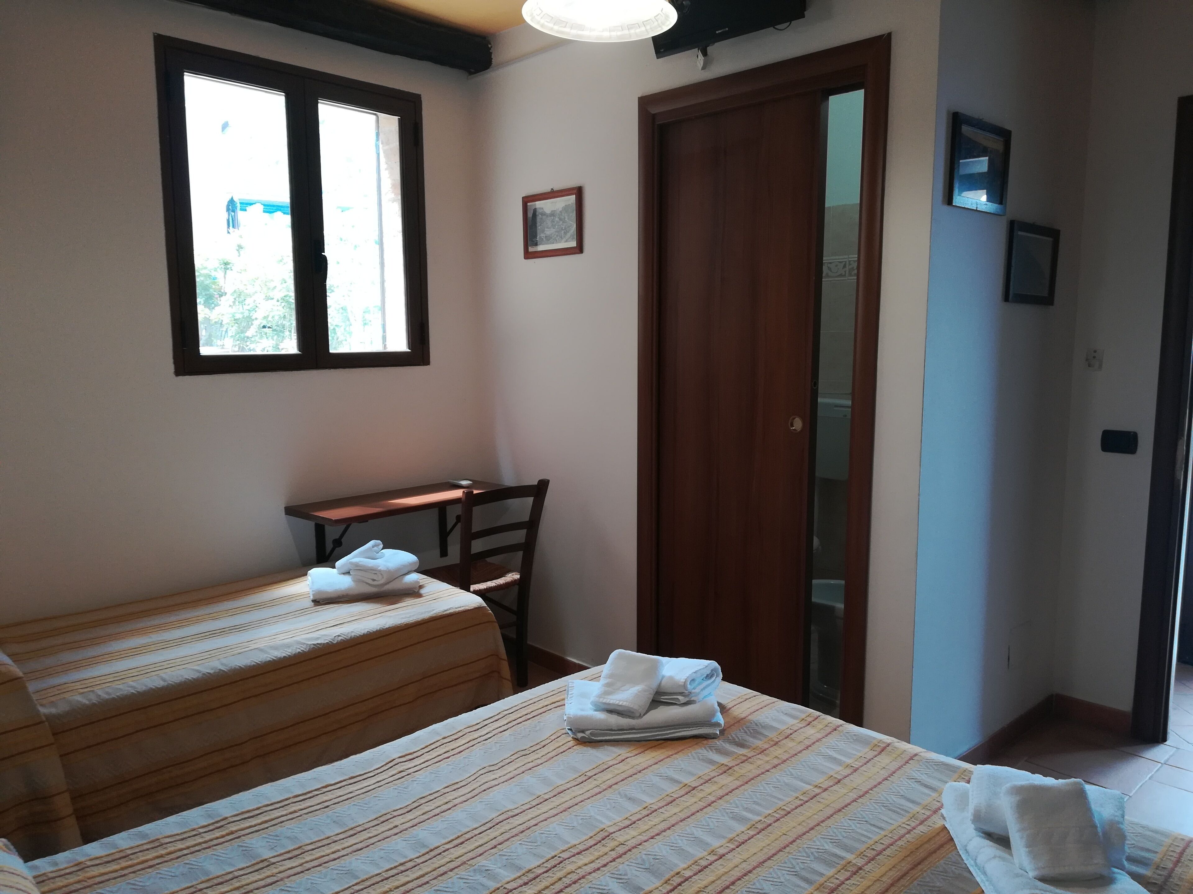 Una habitación con dos camas, un escritorio y una puerta.