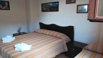 Habitación de hotel con dos camas, una mesita de noche y una pared decorada con cuadros.