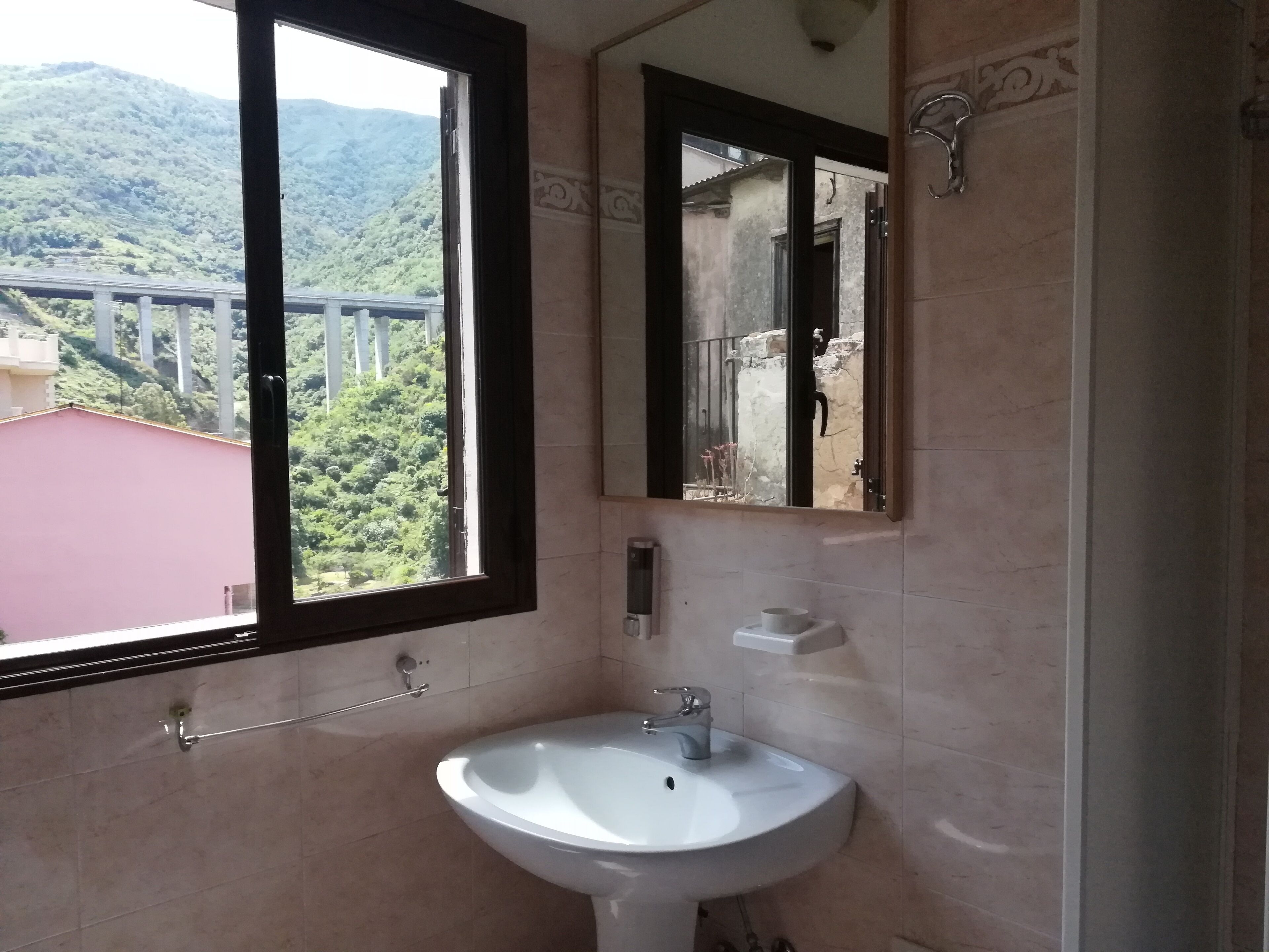 A bathroom with a large window, a sink, and a mirror.